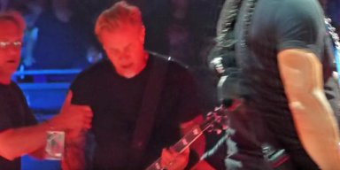 METALLICA's JAMES HETFIELD Falls On Stage At Amsterdam Concert, continues playing the track while grimacing in pain.