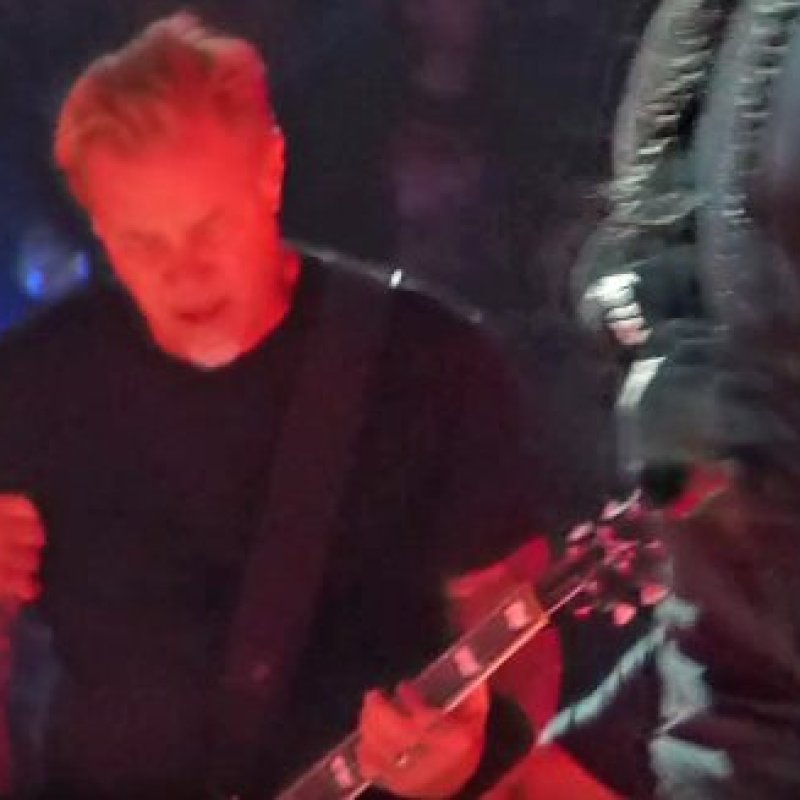 METALLICA's JAMES HETFIELD Falls On Stage At Amsterdam Concert, continues playing the track while grimacing in pain.